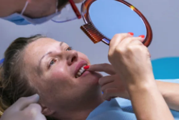 Patient examining her gums in a hand mirror during a dental visit