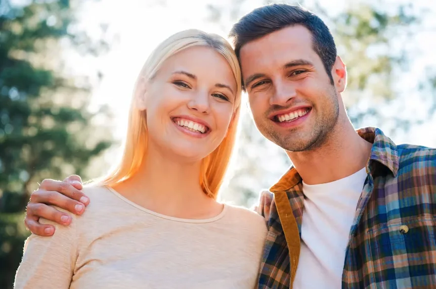 Happy couple smiling outdoors, reflecting healthy gums and overall well-being